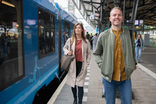 Man en vrouw lopen op perron Blauwnet trein